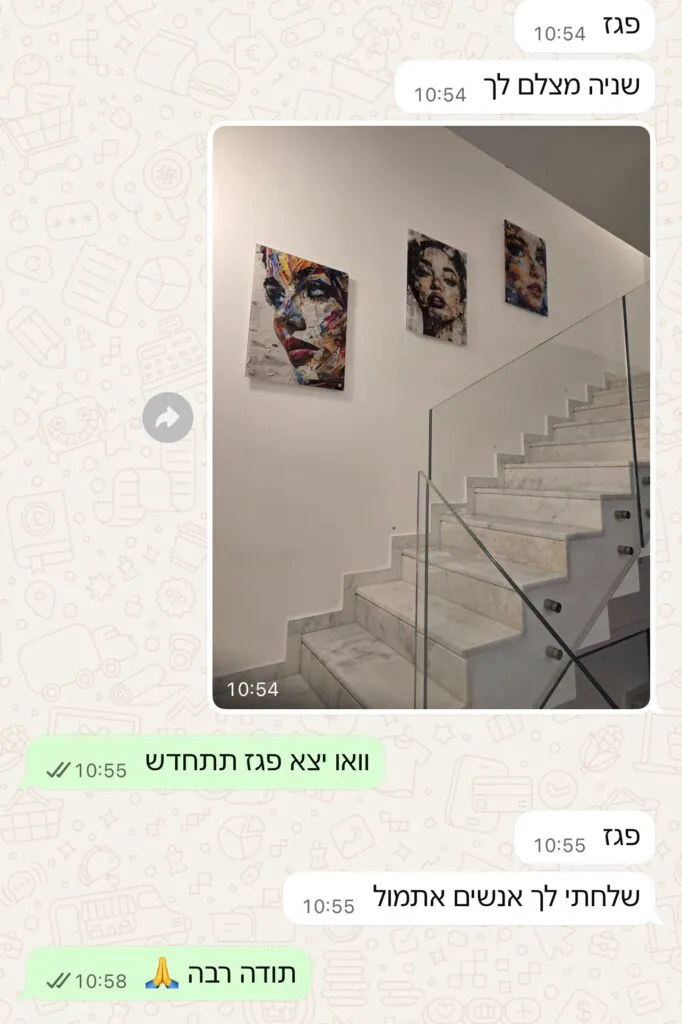 מדרגות שיש לבנות עם מעקה זכוכית ושלוש יצירות אמנות צבעוניות של פנים על הקיר